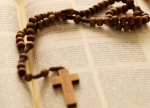 Open Bible with a wooden rosary placed on top — what does the Bible say about tithing and Christian giving