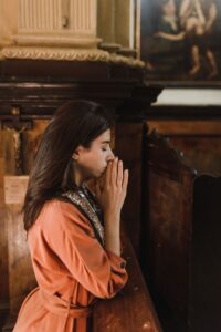 Woman praying reverently inside a vintage church — what happens after death according to the Bible