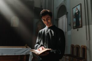 Priest reading the Holy Bible in soft church light — what does the Bible say about tattoos